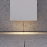 Lite, stilfullt baderom med mørkeblå vegger, myke gule baderomsmøbler med riller, og elegant rundt speil med lampe.