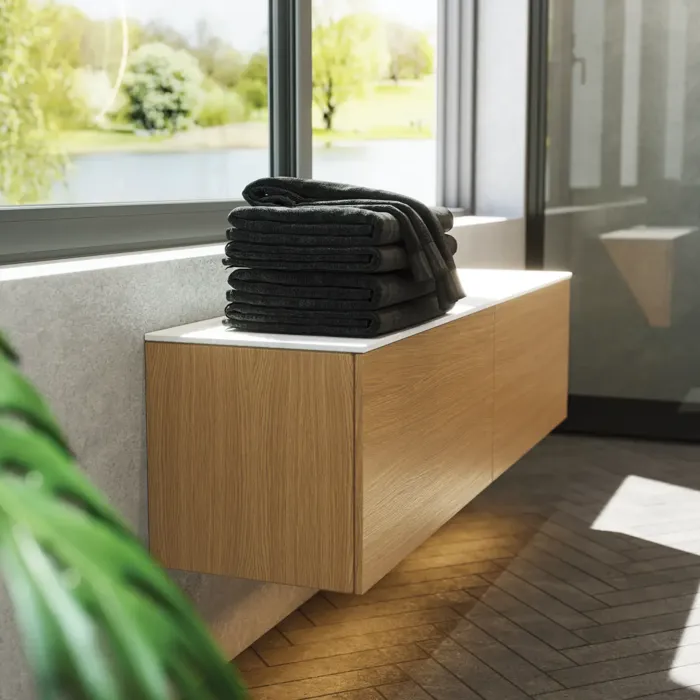 Minimalistisk og stilren baderomsinspirasjon med servantskap, underskap og høyskap i gyllen eik, stort rundt speil med lysstyring, farget toalett og bordstående servant