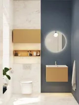 Lite, stilfullt baderom med mørkeblå vegger, myke gule baderomsmøbler med riller, og elegant rundt speil med lampe