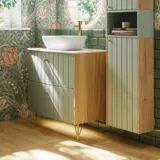 Baderomsinspirasjon med baderomsmøbler i grønn spesialfarge med sider i naturlig eik, elegante riller, stilfull benkeplate med romantisk oval bordstående servant, vakkert ovalt speil, gir sammen med blomstrete tapet et yndefullt, vintage retro uttrykk.