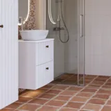 Stor baderomsinspirasjon med hvite møbler med riller, elegante benkeplater og bordstående servanter, ovale speil med lys, synlige bjelker og mønstrede fliser gir et vintage og stilfullt uttrykk