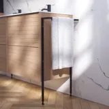 Baderomsinspirasjon med vaskeskap samt overskap i lys eik med lameller, elegant dobbel servant, vakkert speilskap med lys, fiskebensgulv i lyst tre og hvit marmorvegg gir et klassisk, lyst og stilrent uttrykk.