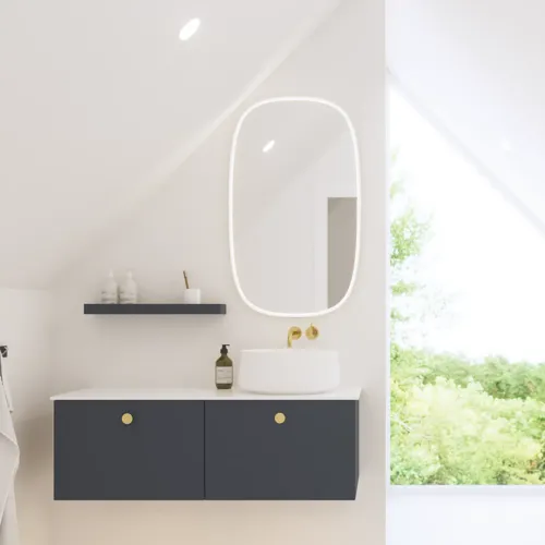 Elegant og moderne baderomsinspirasjon med skråtak, vegghengte blå servantskap og underskap, rund servant med messingarmatur, opplyst speil og naturlig lysinnfall