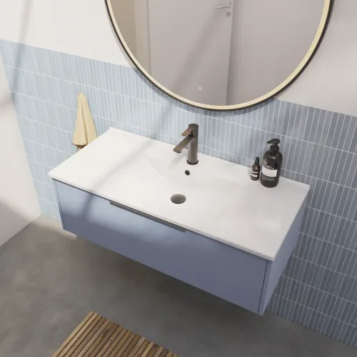Baderomsinspirasjon med avlange lyseblå fliser og betongulv, elegant vaskeskap i lys blå med vakre smale striper, stilren og tynn vask samt minimalistisk rundt speil med svart kant og lys, som gir et snev av eleganse til baderommet ditt.