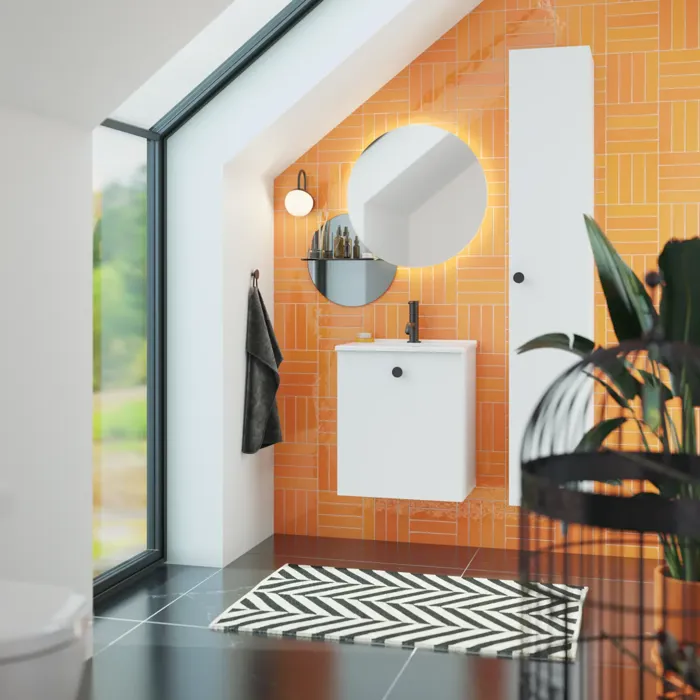 Bad med skråtak inspirert av et lite hvitt servantskap og høyskap med runde, svarte håndtak, samt et vakkert rundt speil og oransje fliser som gir et friskt og moderne uttrykk.