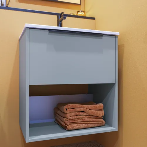 Liten baderomsinspirasjon med skrå og varme gule vegger, elegant vaskeskap i lys blå med åpen hylle som skaper en unik atmosfære, tynn og stilren vask som tilfører både praktikk og eleganse til baderommet ditt.